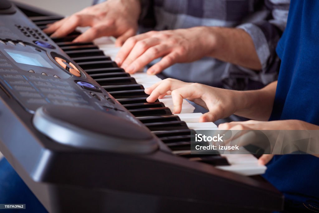 Trainer teaching piano to boy in class Midsection of male teacher teaching piano to male student. Pre-adolescent boy is learning in music class. They are at conservatory. 12-13 Years Stock Photo