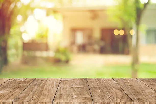 Photo of wooden table space with green home backyard view blur background for advertising template