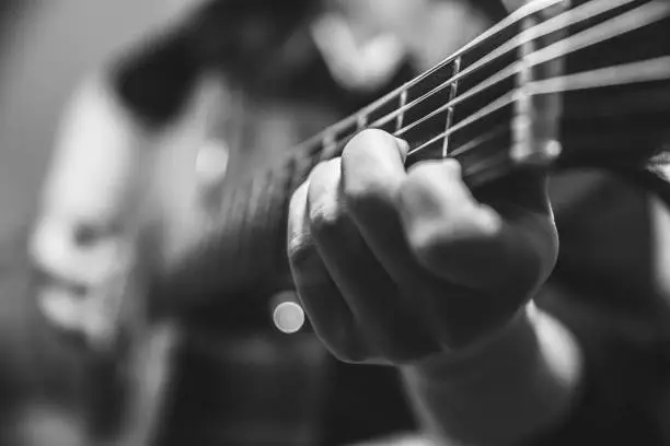 Photo of musician guitar player plays the guitar closeup vintage tone with noise grain effect