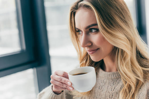istock cheerful woman smiling while holding cup with tea 1151147415