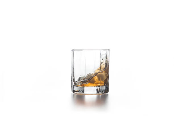 istock Whiskey splash in glass with ice on light background. 1151147866