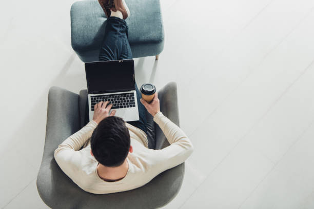 istock top view of man holding paper cup and using laptop with blank screen 1151148962