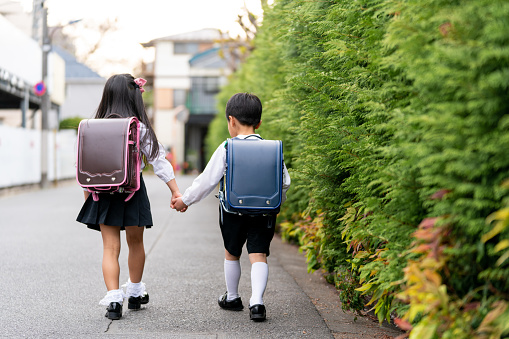 Young brother and sister walking to school together holding hands. Tokyo, Japan