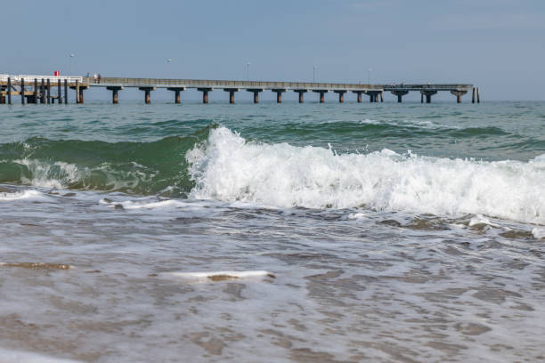 istock Waves crash on the beach with a pier on the coast 1151151787