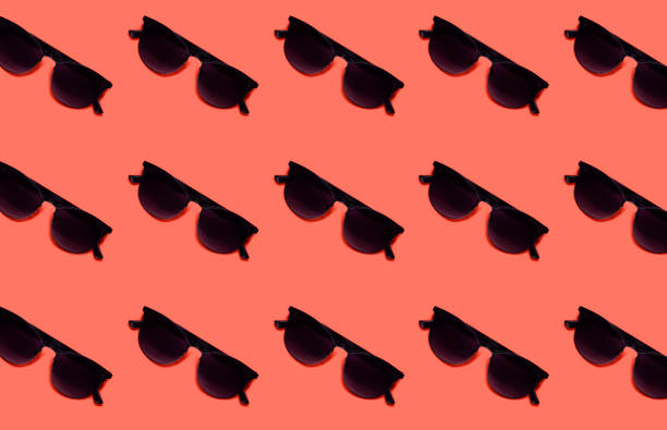 istock Summer pattern made with black sunglasses on coral color background. Minimal vacation, summer or fashionable trendy concept. 1151151806