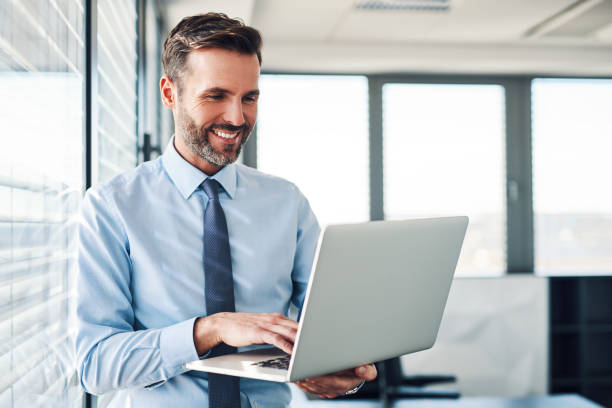 Handsome businessman in modern office looking on laptop Handsome businessman in modern office looking on laptop man laptop stock pictures, royalty-free photos & images