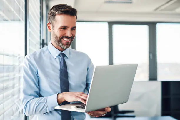 Photo of Handsome businessman in modern office looking on laptop