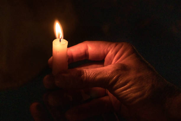 ręka trzyma zapaloną świecę z czarnym tłem. - lighting equipment illuminated isolated on black part of zdjęcia i obrazy z banku zdjęć