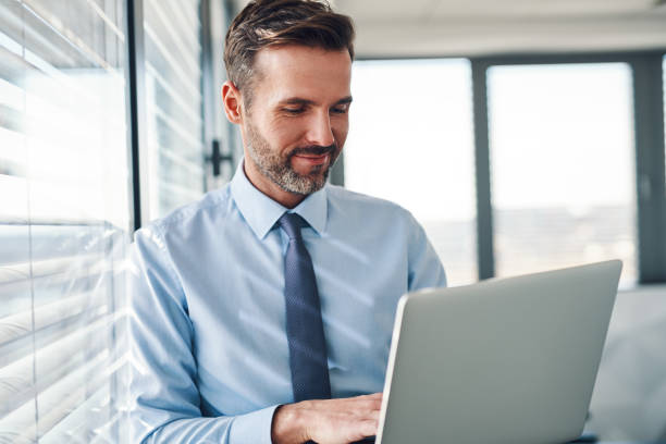 istock Handsome businessman in modern office looking on laptop computer 1151152139