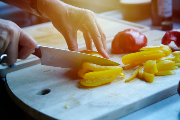 Roughly chopped tomato falling off a cutting board into a stainless steel pan