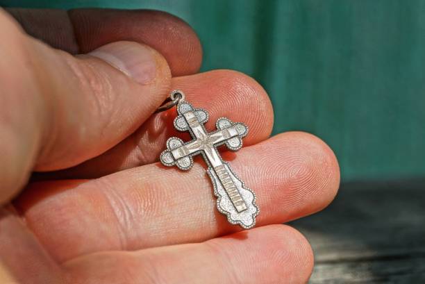 istock small gray silver cross is lying on the fingers 1151153271