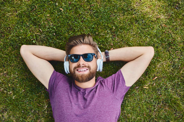 szczęśliwy człowiek słucha muzyki r. na trawie w parku. - image date audio zdjęcia i obrazy z banku zdjęć