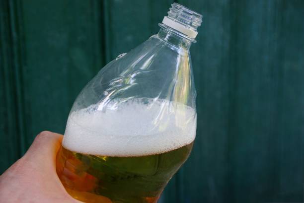 istock hand holding a plastic bottle with a yellow drink and white foam 1151153672