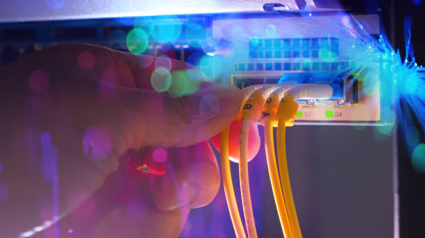 ręka inżyniera systemu i żółty kabel światłowodowy na przełączniku routera z oświetleniem światłowodów w pomieszczeniu centrum danych technologii. panoramiczny - high speed technology cable computer network zdjęcia i obrazy z banku zdjęć