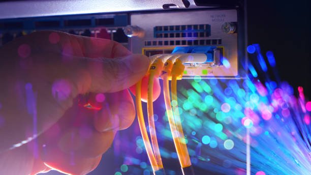 Hand of system engineer and Yellow fiber optic cable on Router switch with lighting of fiber optics in a technology data center room. widescreen stock photo
