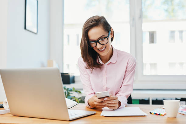 istock Young woman sitting in office and using phone 1151155572