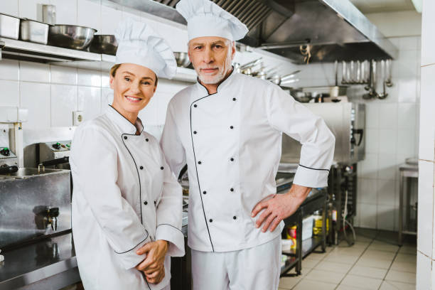 istock female and male chefs in uniform looking at camera and smiling at restaurant kitchen 1151155848
