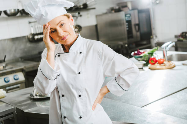 istock beautiful tired female chef in uniform having headache in restaurant kitchen 1151155852
