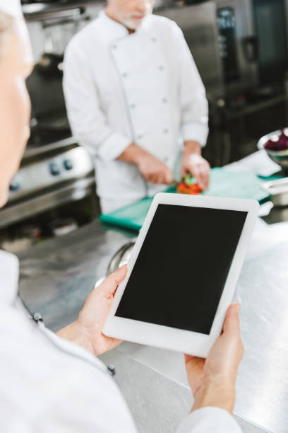 istock partial view of female chef using digital tablet with blank screen in restaurant kitchen 1151155877