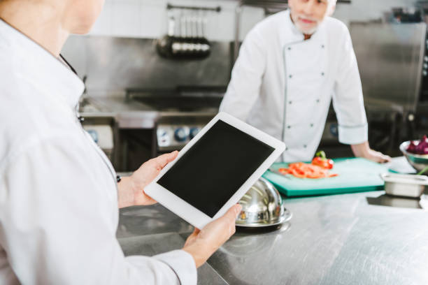 istock partial view of female chef using digital tablet with blank screen in restaurant kitchen 1151155879