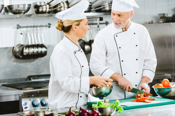 istock female and male chefs in uniform cutting ingredients while cooking in restaurant kitchen 1151157352