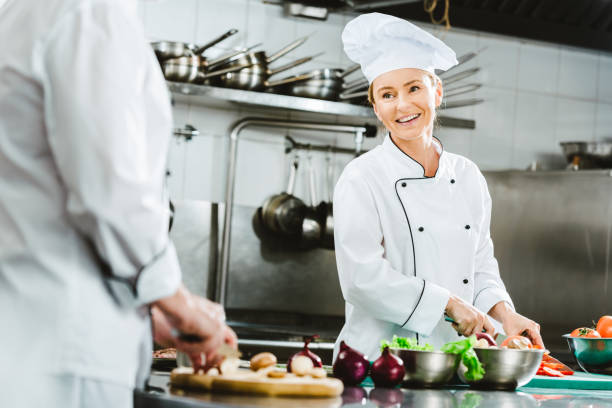 istock beautiful female chef in uniform smiling while cooking in restaurant kitchen 1151157361