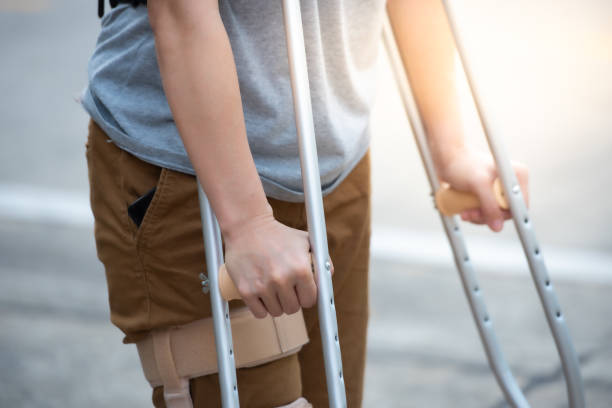 donna disabile con stampelle o bastone da passeggio o supporto al ginocchio in piedi sul retro, metà corpo. - crutch foto e immagini stock