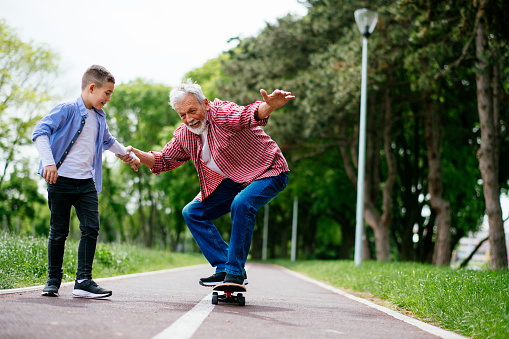Grandfather and grandson skateboarding together. Shadow DOF. Developed from RAW; retouched with special care and attention; Small amount of grain added for best final impression. 16 bit Adobe RGB color profile.