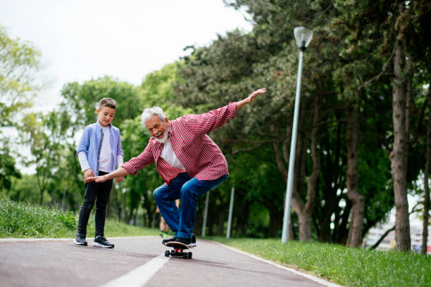 kleiner junge versucht skateboard - grandfather grandson active seniors senior adult stock-fotos und bilder