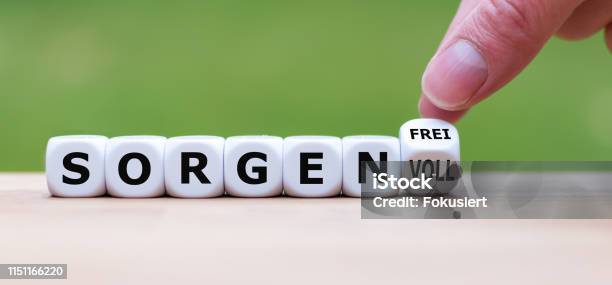 Hand Turns A Dice And Changes The German Word Sorgenvoll Stock Photo - Download Image Now