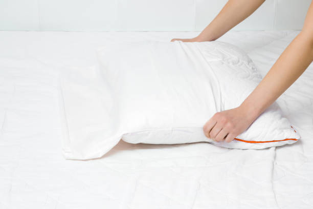istock Woman's hands on mattress surface changing white cotton cover on pillow. Regular bed linen change. Closeup. 1151168426