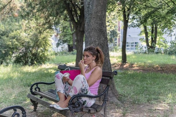 istock Beautiful Young Woman Eats Ice Cream in a Public Park. 1151168738