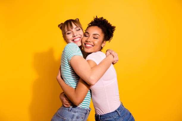 Portrait of charming cute pretty ladies cuddle tender gentle positive bun close eyes wear modern trendy style stylish t-shirt jeans wavy curly hairdo isolated on yellow background Portrait of charming cute pretty ladies cuddle tender gentle positive bun close eyes wear modern trendy style stylish t-shirt jeans wavy curly hairdo isolated on yellow background. two people embracing stock pictures, royalty-free photos & images