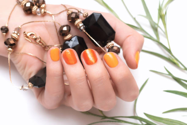 istock Female hand with orange nail design on white background 1151180420