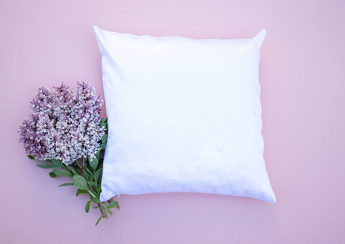 Blank white square cushion on pink background with lilac flowers mock up - flat lay