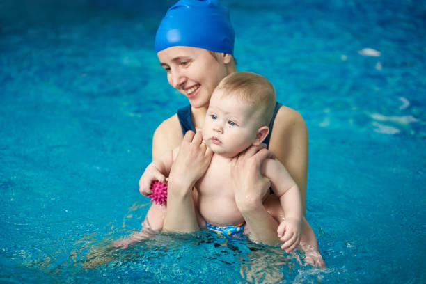 istock Mother standing in water, holding her little son doing exercise during wellness water treatments for infants in pool 1151180698
