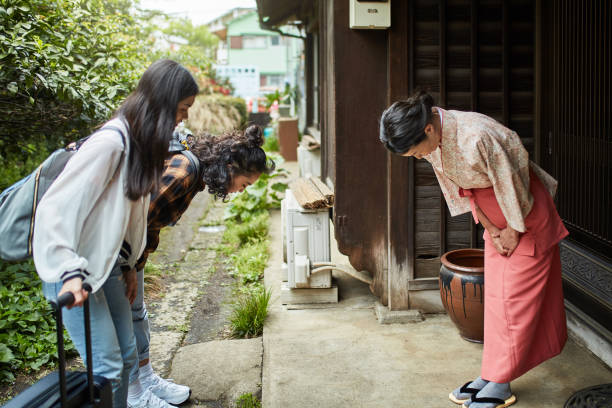 landlady greeting female guests outside ryokan - bowing imagens e fotografias de stock