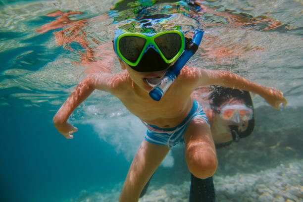 enfant apprenant à plonger avec sa mère dans la mer. - peu profond photos et images de collection