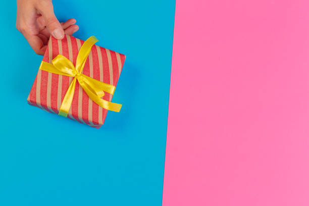 istock Woman holding gift box on color background 1151186912