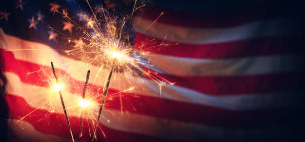 Sparklers And American Flag - Independence Day Vintage Celebration With Sparklers And Defocused American Flag - Independence Day fourth of july photos stock pictures, royalty-free photos & images