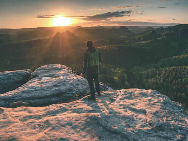 istock Professional photographer stay with tripod on cliff and thinking. 1151187673