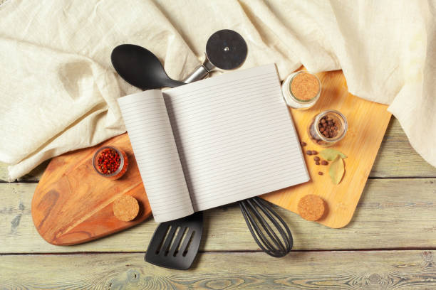 istock Blank sheet of opened notepad and kitchen utensils on  table with tablecloth, copy space 1151189049