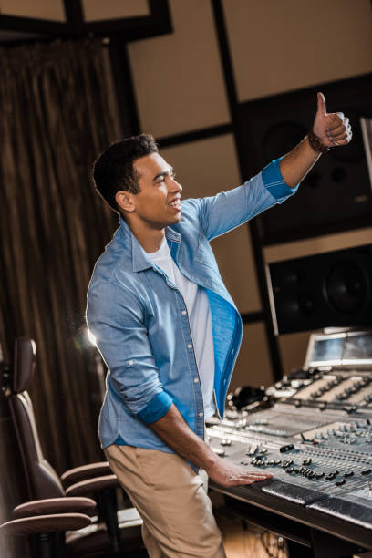 istock smiling mixed race sound producer showing thumb up while working at mixing console 1151191196