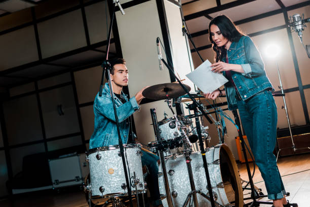istock pretty singer and handsome mixed race drummer talking in recording studio 1151191398