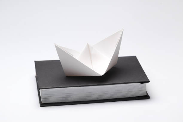 istock Origami paper boat on a book 1151191728