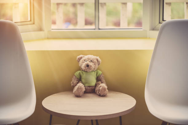 Lonely doll bears near the window with sunlight. Sadness concept in vintage color tone