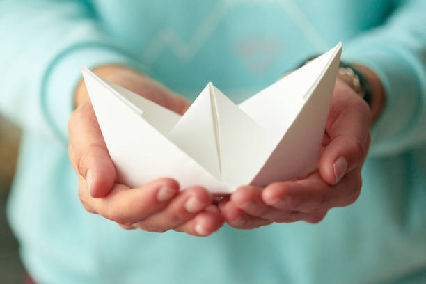 istock White origami boat in woman's hands 1151193203