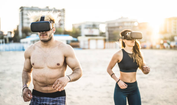 istock Young couple running at beach with virtual reality goggles headset - Sport and technology concept with friends jogging and exercising on trek simulation on summer time - Contrast sunset filter 1151195272
