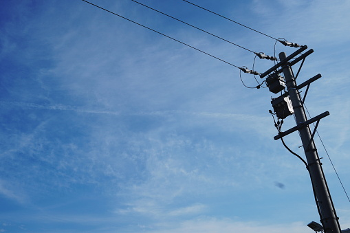 Old simple rural wood electrical pole on blue sky.