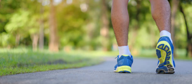 young fitness man legs running in the park outdoor, male runner walking on the road outside, asian athlete jogging and exercise on footpath in sunlight morning. Sport, healthy and wellness concepts piernas de hombre de fitness joven corriendo en el parque al aire libre, corredor masculino caminando en la carretera fuera, atleta asiático de jogging y ejercicio en el sendero en la luz del sol por la mañana. conceptos deportivos, saludables y de biene